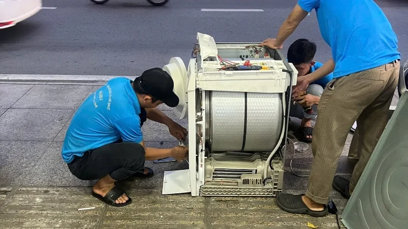 Kỹ thuật viên kiểm tra bo mạch máy giặt tại nhà khách hàng